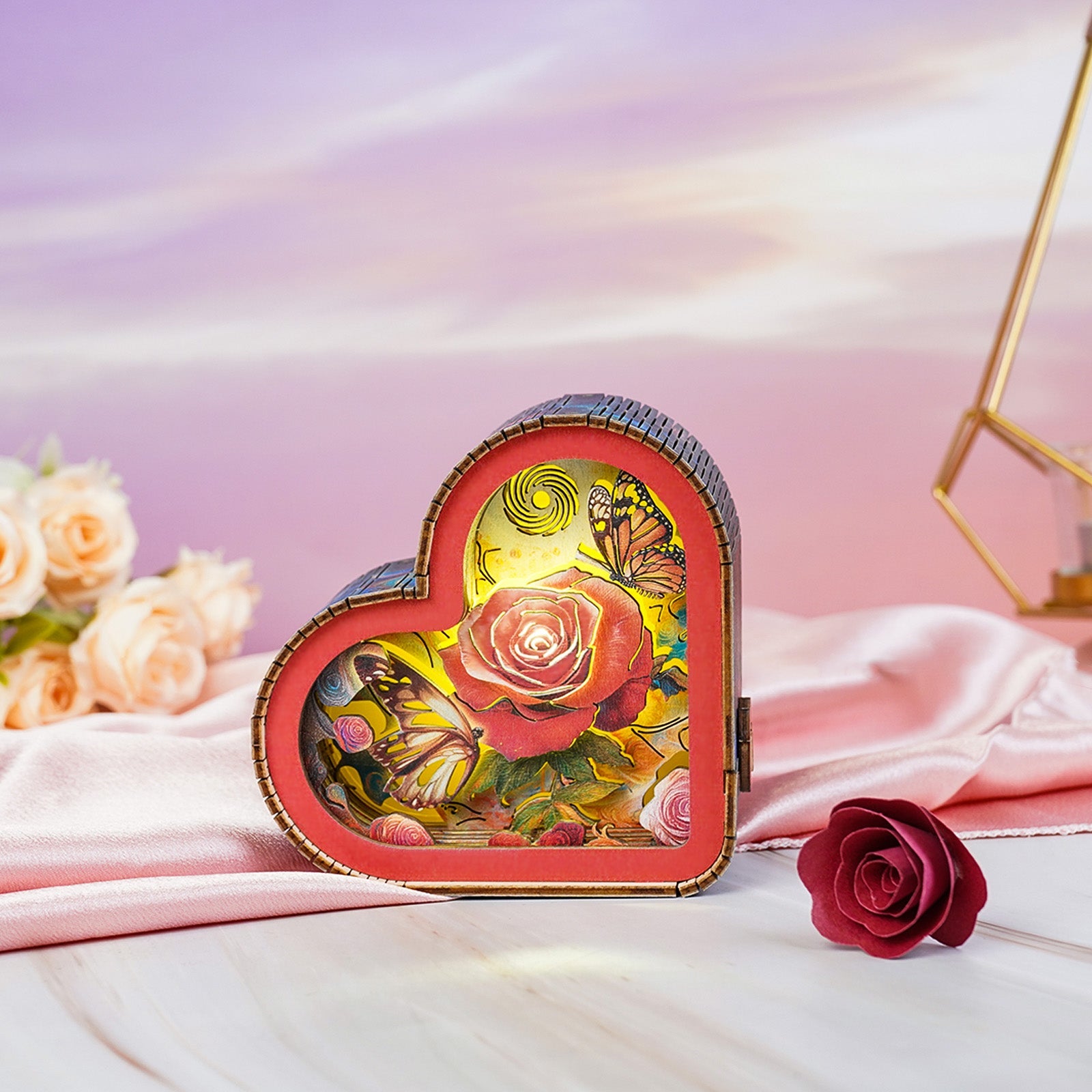 Heart-shaped 3D wooden puzzle night light featuring a rose and butterflies, glowing softly on a pink silk background.